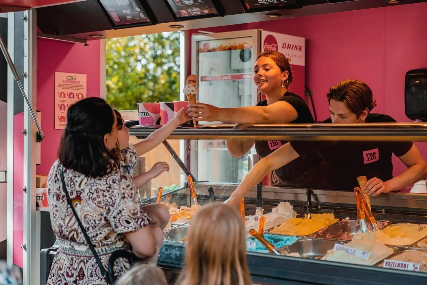 Een medewerker van Frezzo geeft een ijsje aan over de vitrine